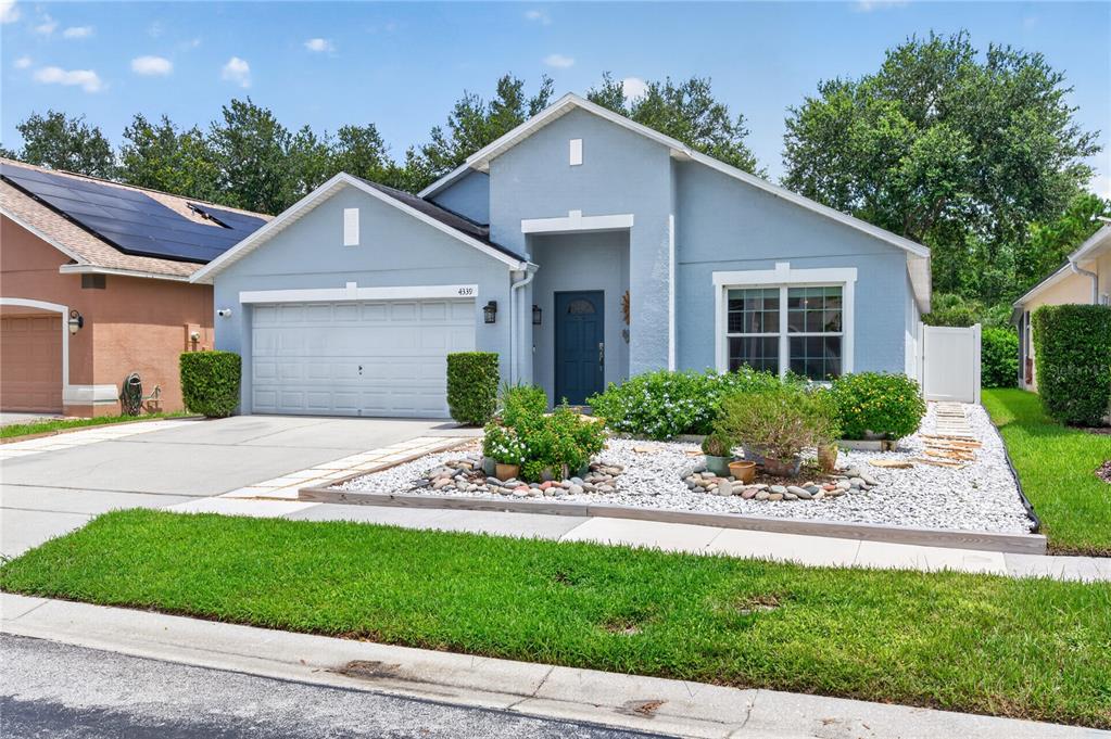 A light blue single-story house features a two-car garage and a paved driveway — 4339 NORTHERN DANCER WAY, ORLANDO, FL