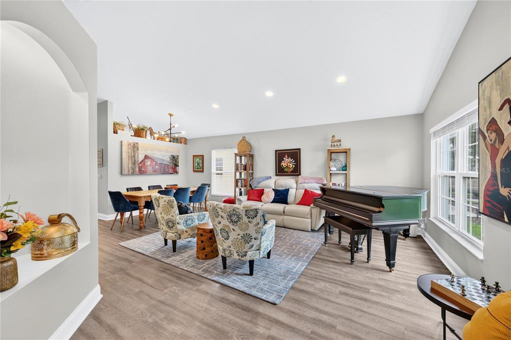 A dining area and living space feature wood-look flooring, an arched wall niche, and furniture — 4339 NORTHERN DANCER WAY, ORLANDO, FL