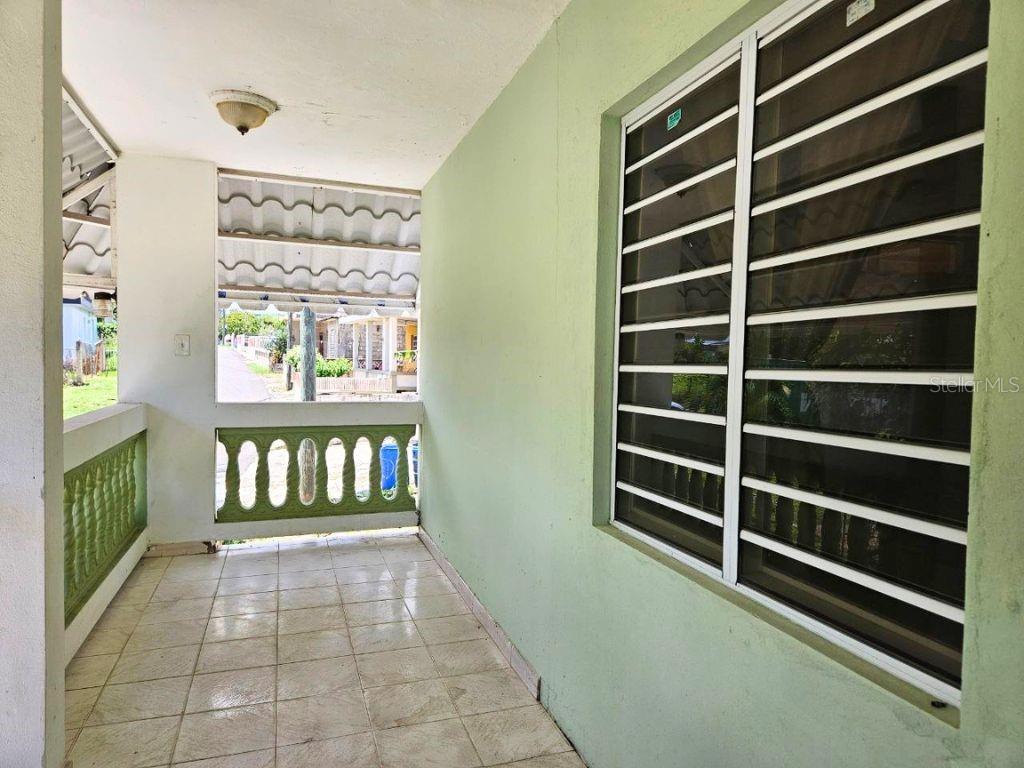 A covered porch with tiled flooring, green walls, and a window with metal security bars — Car 2 R 485 K2 H2 Bo Memb SECTOR BAJURA CAMUY, CAMUY, PR