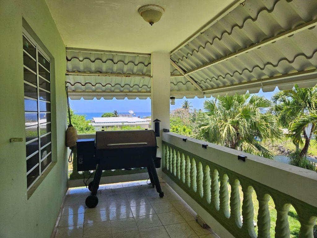 A covered balcony features a grill, tiled flooring, and a view of the ocean — Car 2 R 485 K2 H2 Bo Memb SECTOR BAJURA CAMUY, CAMUY, PR
