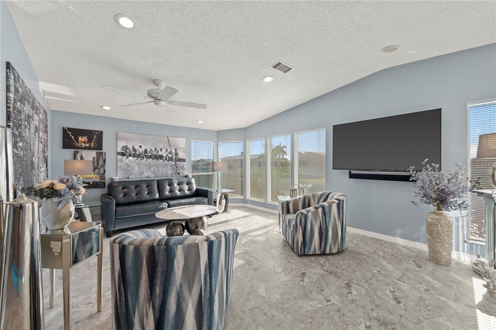 A living room features a dark leather sofa, two patterned armchairs, and a wall-mounted television — 39 EMDEN CIRCLE, PUNTA GORDA, FL