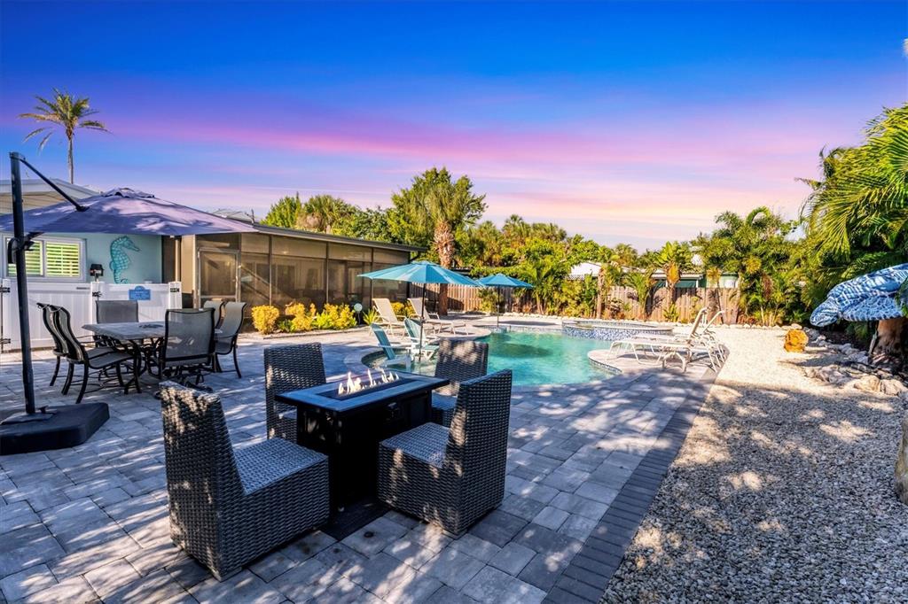 A backyard patio features a fire pit, dining area, swimming pool, and lounge chairs — 154 CRESCENT DRIVE, ANNA MARIA, FL