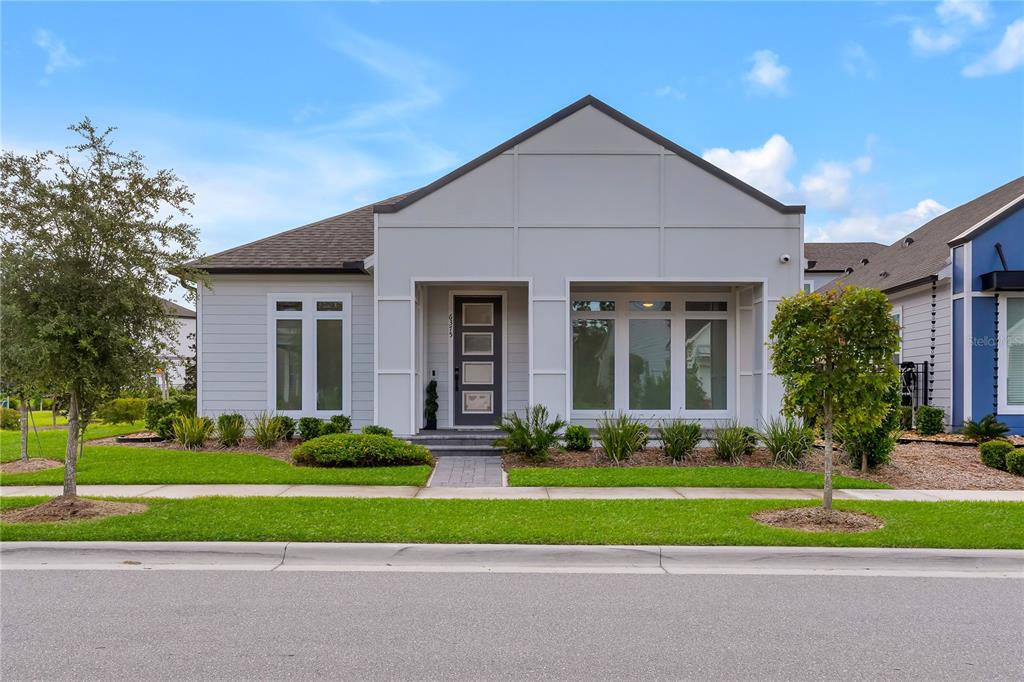 A modern, single-story house with light gray siding and a dark gray front door — 6375 TRAILBLAZE BEND, ST CLOUD, FL