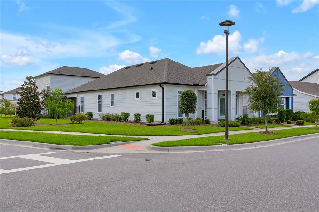 A single-story house with light-colored siding stands on a corner lot with a sidewalk — 6375 TRAILBLAZE BEND, ST CLOUD, FL