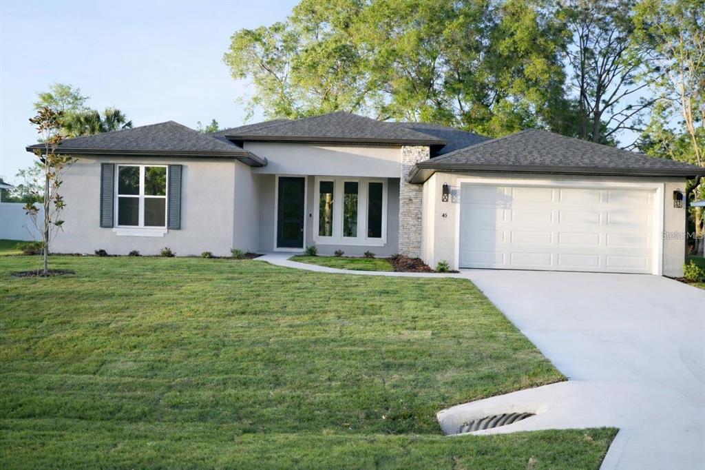 A single-story house with a gray stucco exterior, a two-car garage, and a front lawn — 21 LAMAR LANE, PALM COAST, FL