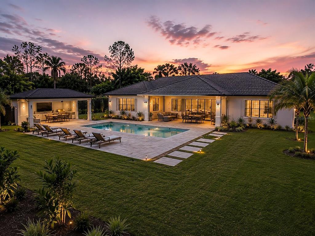 A backyard features a swimming pool, a covered patio with an outdoor kitchen, and landscaping — DE LEON DRIVE, NORTH PORT, FL