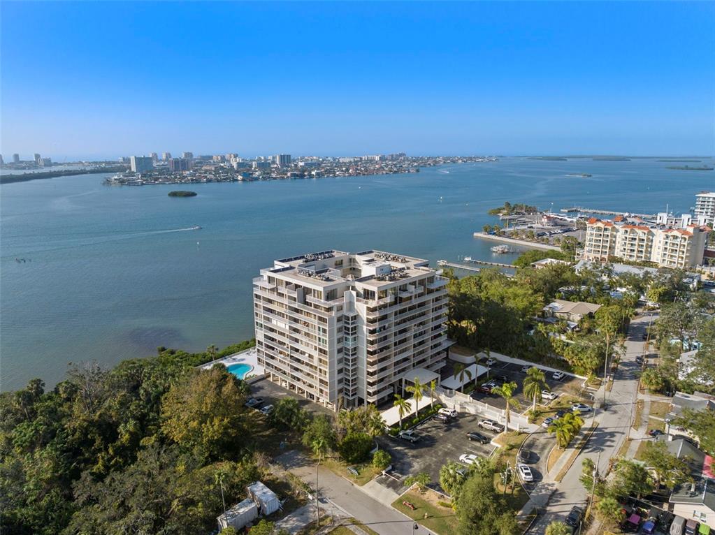 An aerial view shows a swimming pool next to a high-rise building and water — 500 N OSCEOLA AVENUE UNIT 406, CLEARWATER, FL