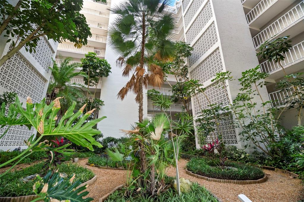 A view from a balcony overlooking a multi-story apartment building's central courtyard and garden — 500 N OSCEOLA AVENUE UNIT 406, CLEARWATER, FL
