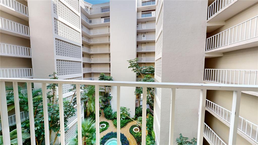 An interior courtyard with lush tropical plants, palm trees, and a small fountain — 500 N OSCEOLA AVENUE UNIT 406, CLEARWATER, FL