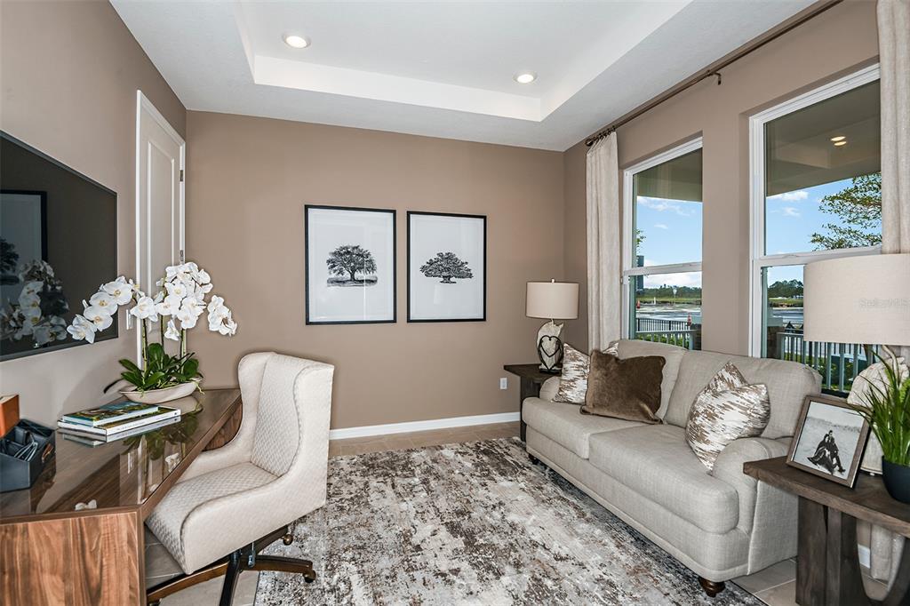 A home office features a desk, sofa, area rug, and two windows overlooking a lake — 712 SKY SHADE DRIVE, APOLLO BEACH, FL