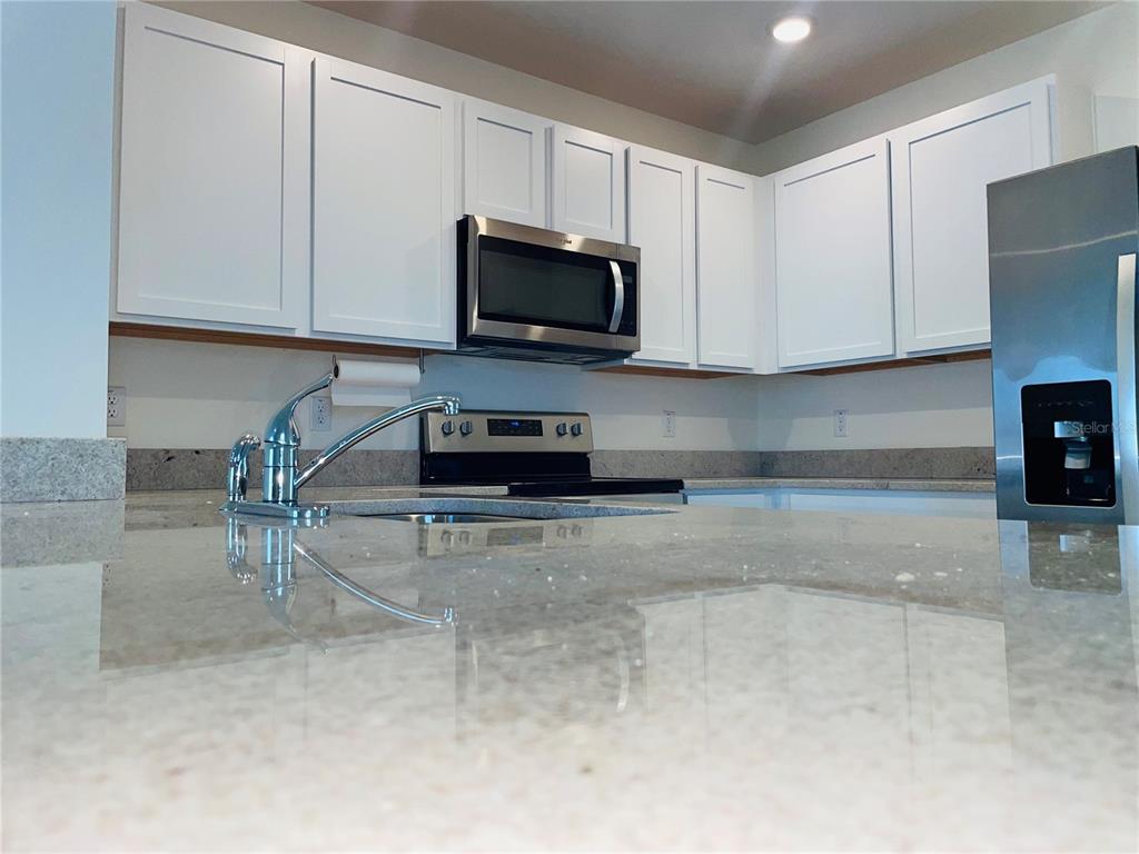 A kitchen features white cabinets, stainless steel appliances, and light-colored granite countertops — 17043 OVAL RUM DRIVE, WIMAUMA, FL