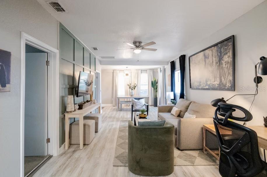 A living room features a green paneled accent wall, light wood flooring, and a dining area — 8311 N NEWPORT AVENUE, TAMPA, FL