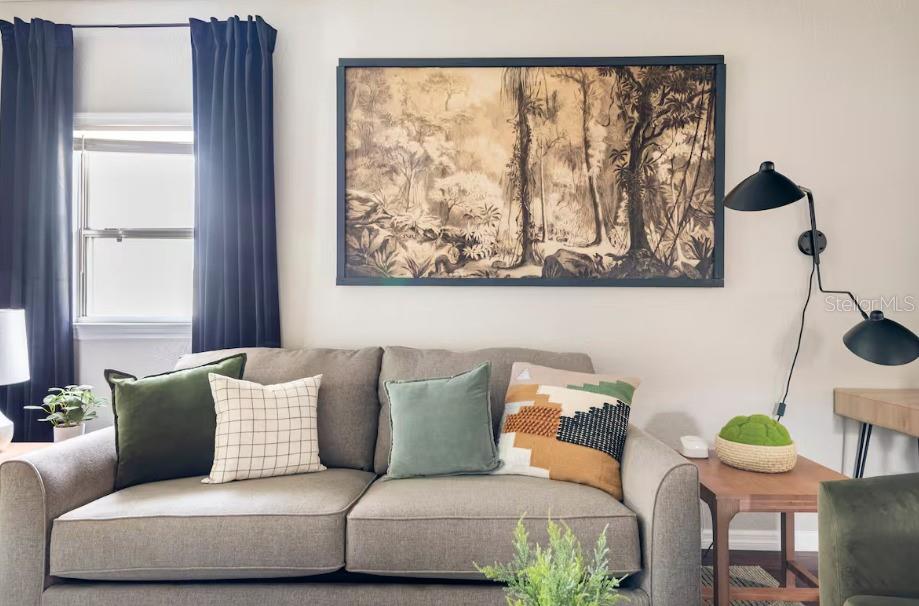 A living room features a gray sofa, wall art, and a black wall-mounted lamp — 8311 N NEWPORT AVENUE, TAMPA, FL