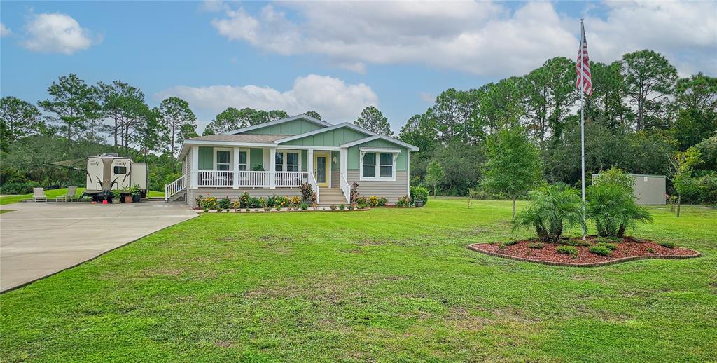 A green and tan house with a front porch sits on a large grassy lot — 875 VOLCO ROAD, EDGEWATER, FL