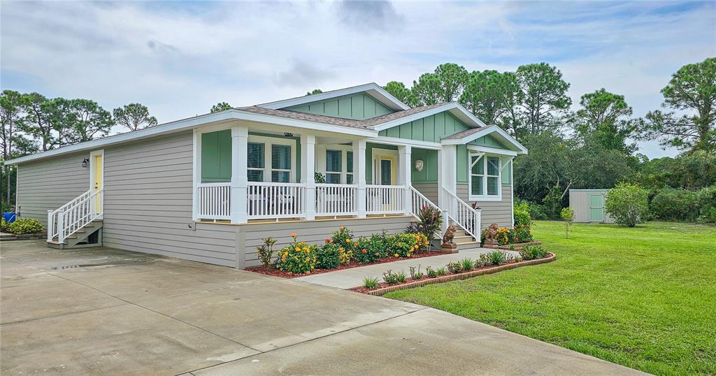 A single-story house with a covered front porch, light-colored siding, and a concrete driveway — 875 VOLCO ROAD, EDGEWATER, FL