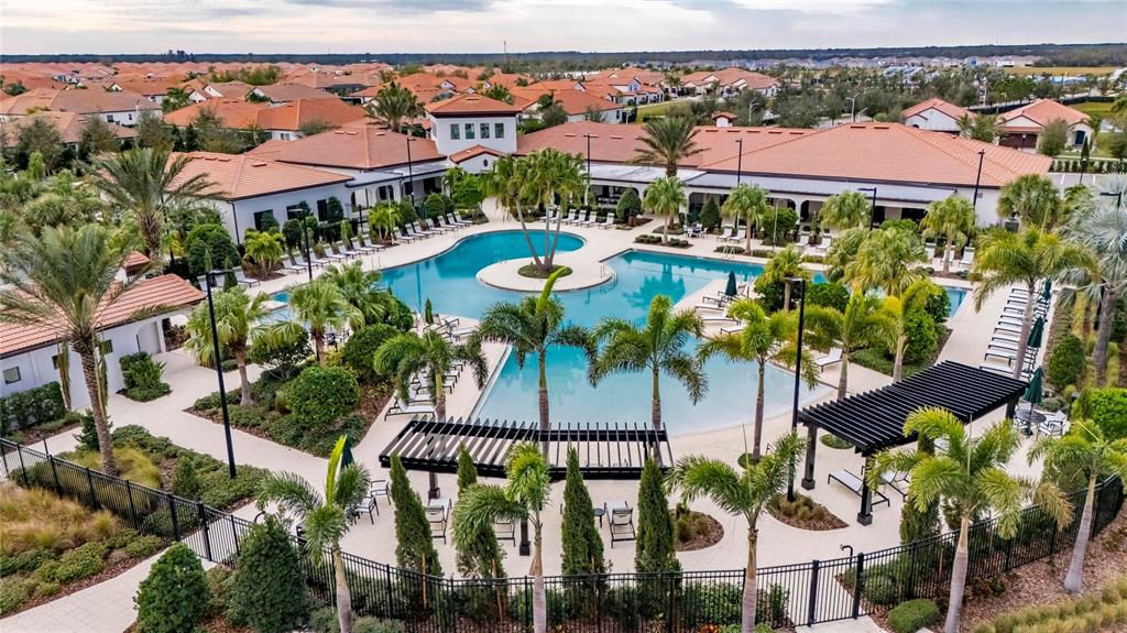An aerial view of a community swimming pool surrounded by palm trees and residential buildings — 17334 HOLLY WELL AVENUE, WIMAUMA, FL
