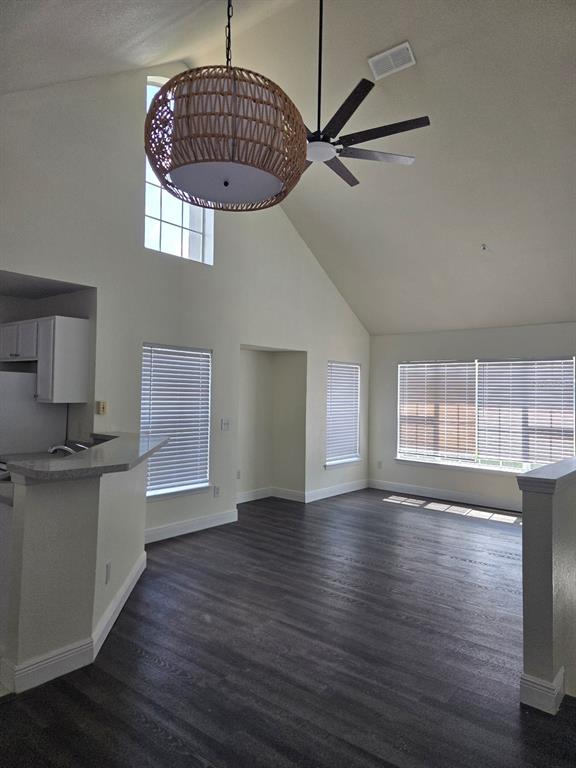 An open living area features vaulted ceilings, dark wood-look flooring, and a large woven pendant light — 9141 LEE VISTA BOULEVARD UNIT 308, ORLANDO, FL