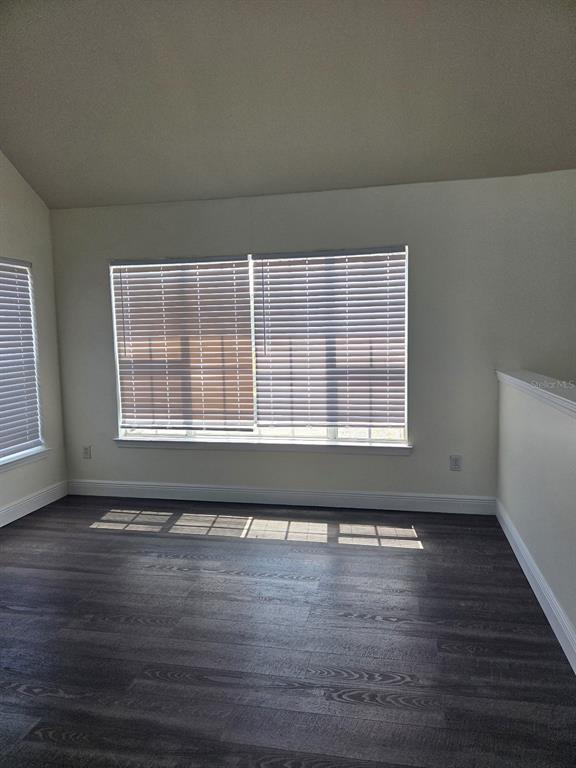 An empty room with dark wood-look flooring, white walls, and windows with closed blinds — 9141 LEE VISTA BOULEVARD UNIT 308, ORLANDO, FL