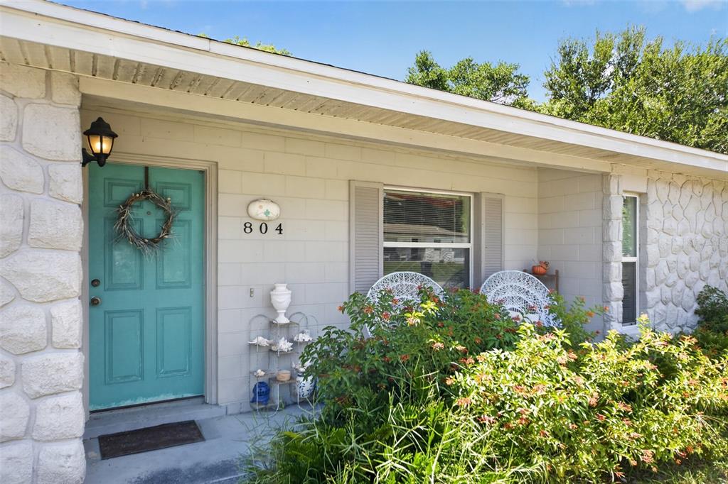 The exterior of a house features a teal front door, stone siding, and a garden — 804 WALNUT PLACE, ALTAMONTE SPRINGS, FL