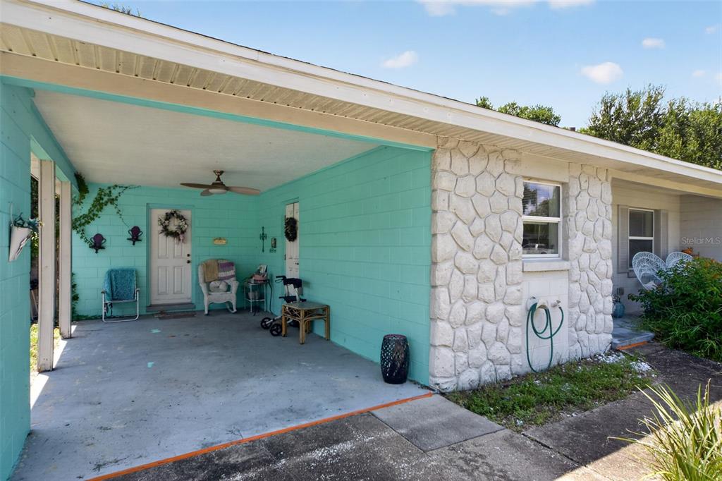 A turquoise-painted carport features a concrete floor, a ceiling fan, and a stone-faced exterior wall — 804 WALNUT PLACE, ALTAMONTE SPRINGS, FL