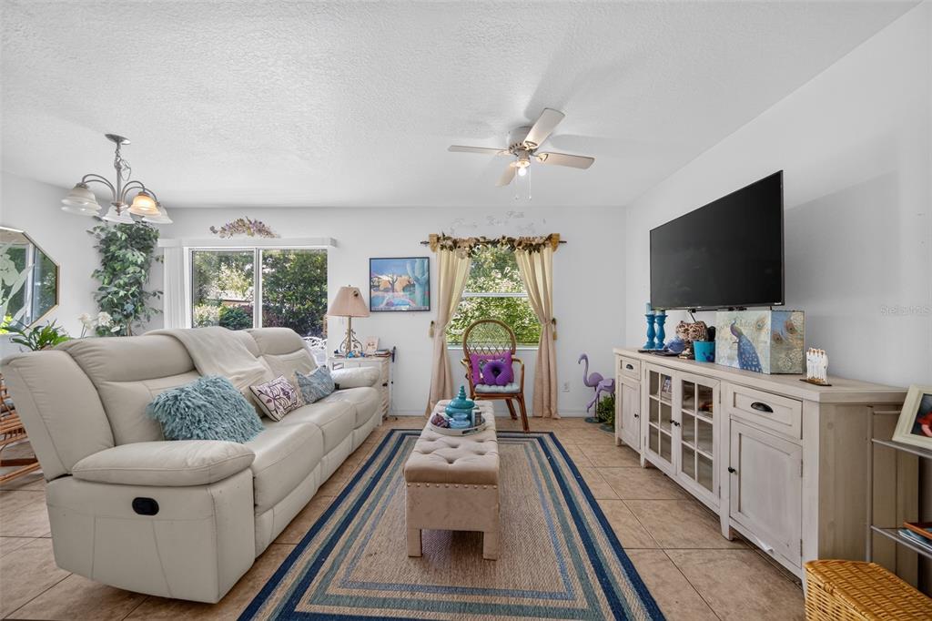 A living room features a white leather sofa, a tufted ottoman, and a television stand — 804 WALNUT PLACE, ALTAMONTE SPRINGS, FL