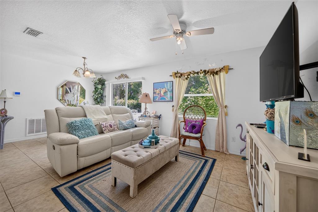 A living room features a white sofa, a tufted ottoman, and a television on a console — 804 WALNUT PLACE, ALTAMONTE SPRINGS, FL