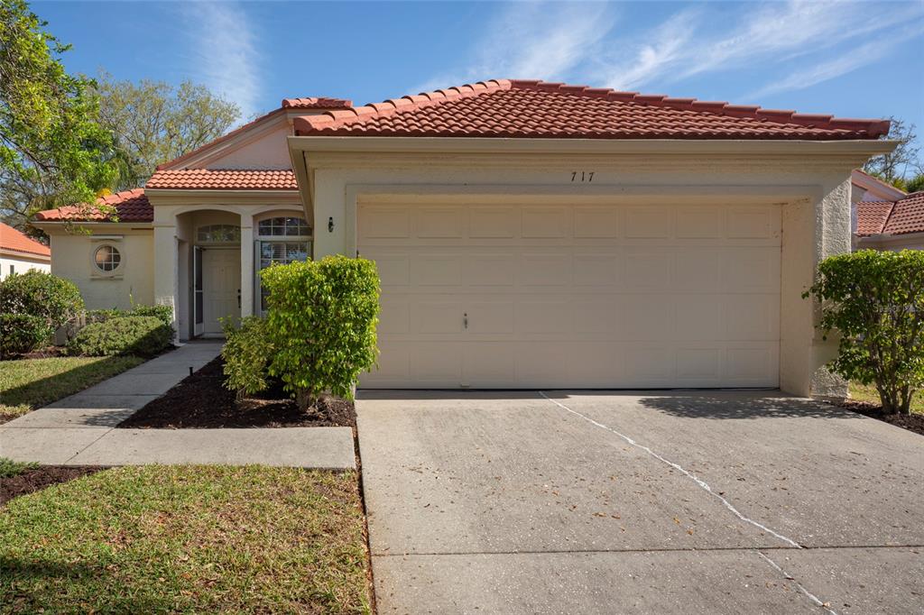 A single-story house with a beige stucco exterior, a tile roof, and a two-car garage — 717 LIGHTHOUSE DRIVE, TARPON SPRINGS, FL