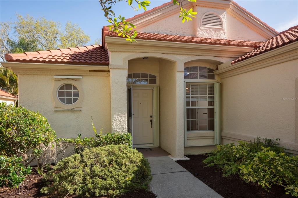 The exterior of a single-story house features a tiled roof, stucco walls, and a front entrance — 717 LIGHTHOUSE DRIVE, TARPON SPRINGS, FL