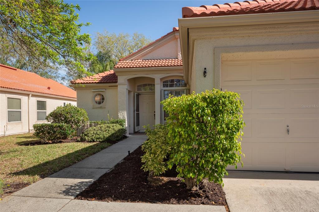 A beige house exterior features a tiled roof, a garage, and a front walkway — 717 LIGHTHOUSE DRIVE, TARPON SPRINGS, FL