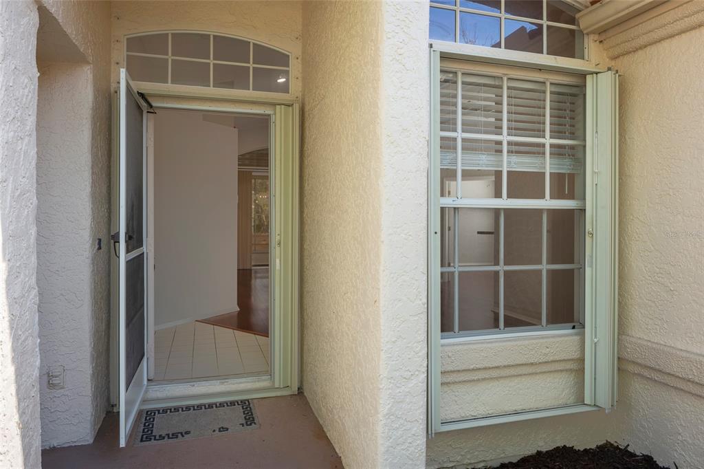 An exterior view of a home entrance featuring a screen door and a window — 717 LIGHTHOUSE DRIVE, TARPON SPRINGS, FL