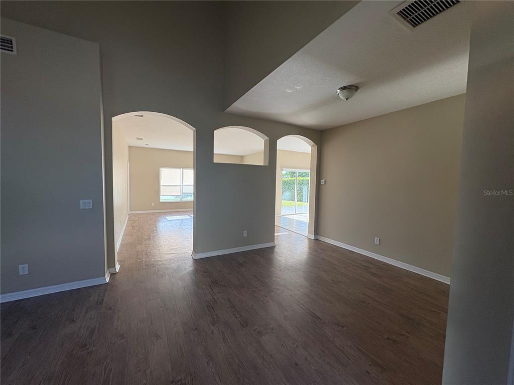 An interior view shows a living area with wood-look flooring and arched wall openings — 6127 46TH STREET E, BRADENTON, FL