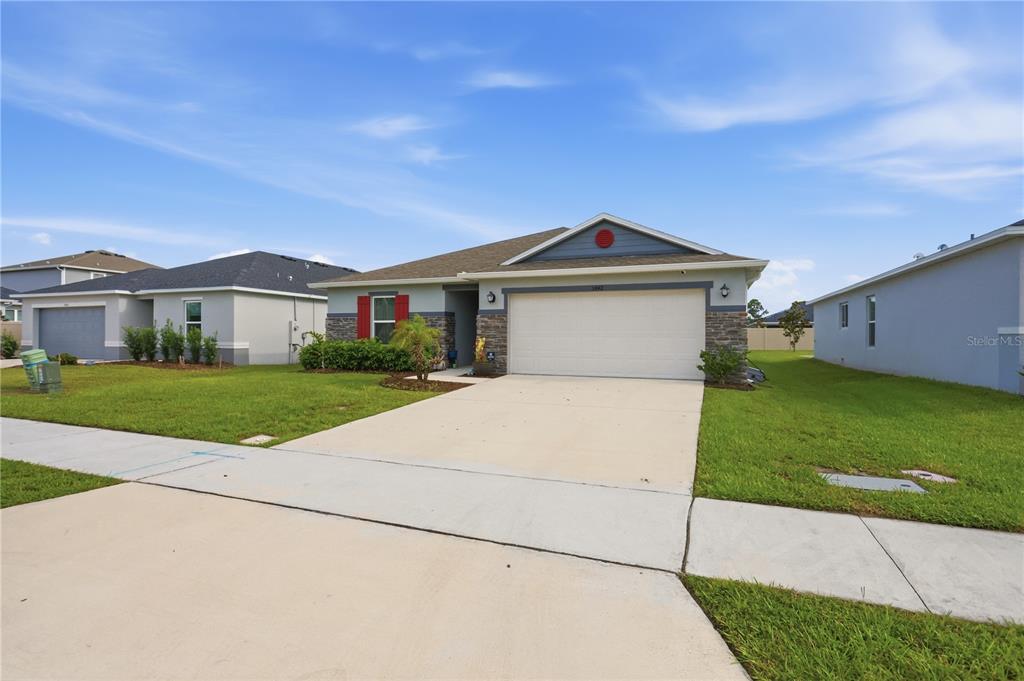 A single-story suburban house with a two-car garage, stone accents, and a concrete driveway — 3842 WHITETAIL COURT, ST CLOUD, FL