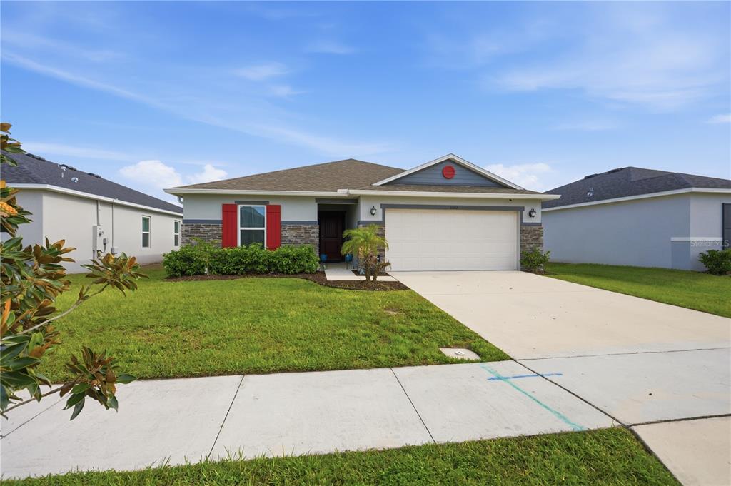 A single-story suburban house with a two-car garage, stone accents, and red window shutters — 3842 WHITETAIL COURT, ST CLOUD, FL