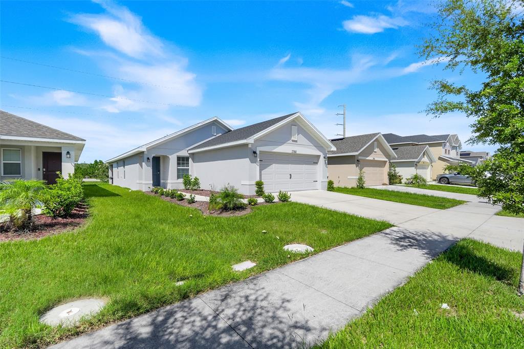 A light-colored single-story house with a two-car garage and a front lawn — 3768 SAGEFIELD DRIVE, ST CLOUD, FL