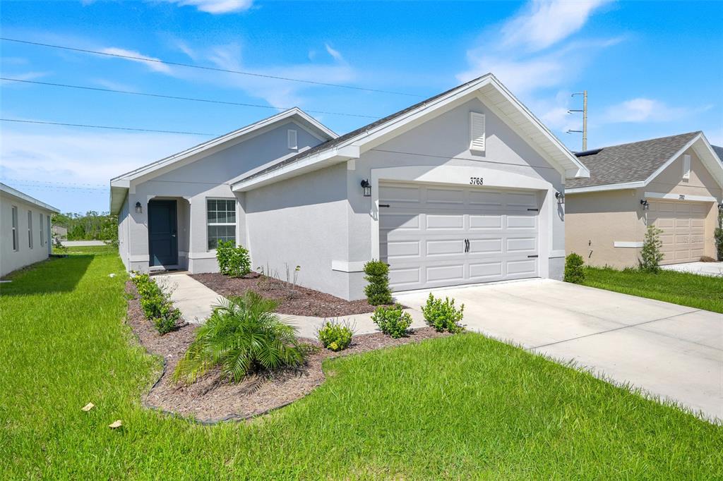 A single-story house with a light gray exterior, a two-car garage, and a front walkway — 3768 SAGEFIELD DRIVE, ST CLOUD, FL