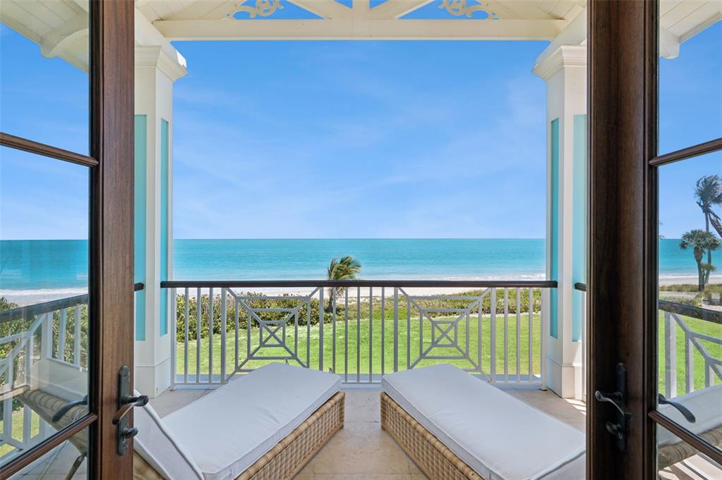 A covered balcony with two lounge chairs overlooks a grassy lawn and the ocean — 716 REEF ROAD, VERO BEACH, FL