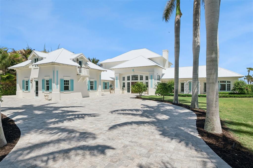 A large white house with turquoise shutters and a paved driveway sits under palm trees — 716 REEF ROAD, VERO BEACH, FL