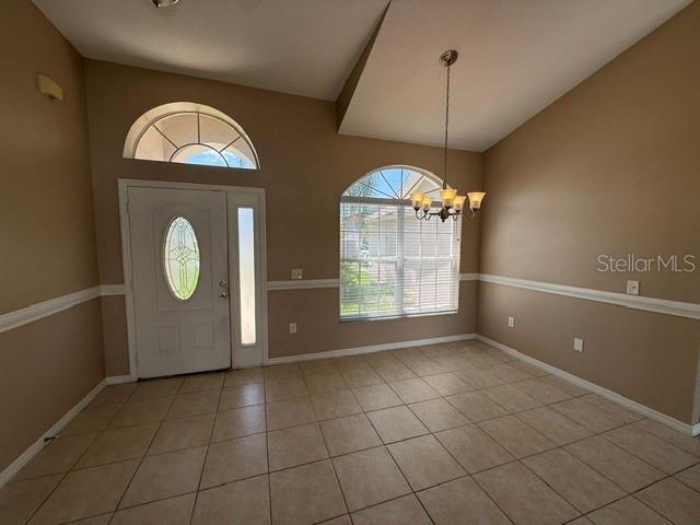 An entryway and dining area with tile floors, a chandelier, and an arched window — 74 ALTERA COURT, KISSIMMEE, FL