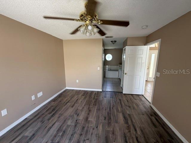 A bedroom with wood-look flooring, a ceiling fan, and an open doorway to a bathroom — 74 ALTERA COURT, KISSIMMEE, FL