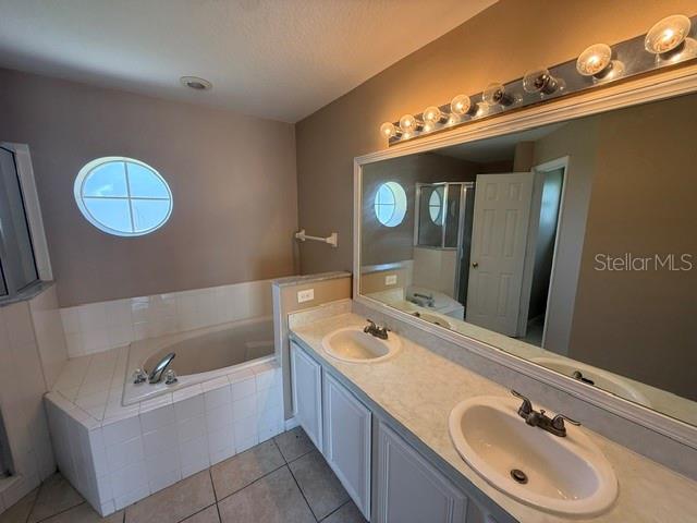 A bathroom featuring a double vanity with white cabinets, a soaking tub, and a large mirror — 74 ALTERA COURT, KISSIMMEE, FL