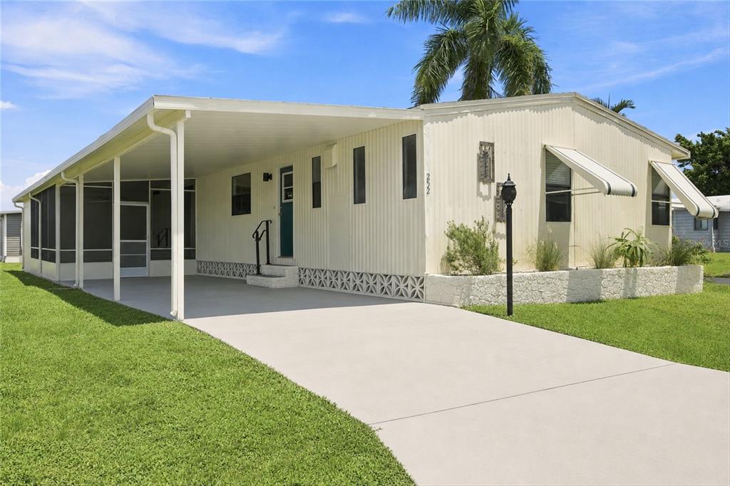 A single-story mobile home with a carport, screened porch, and a concrete driveway — 252 LOON LANE UNIT 252, NAPLES, FL