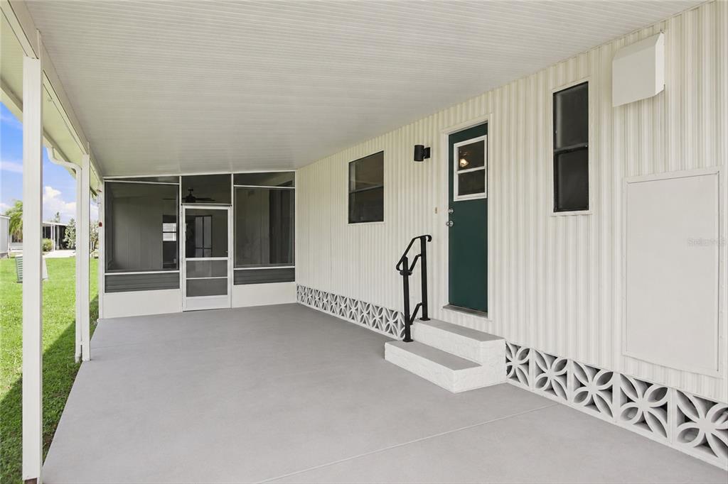 A covered concrete patio features a screened-in area, a green door, and decorative block skirting — 252 LOON LANE UNIT 252, NAPLES, FL