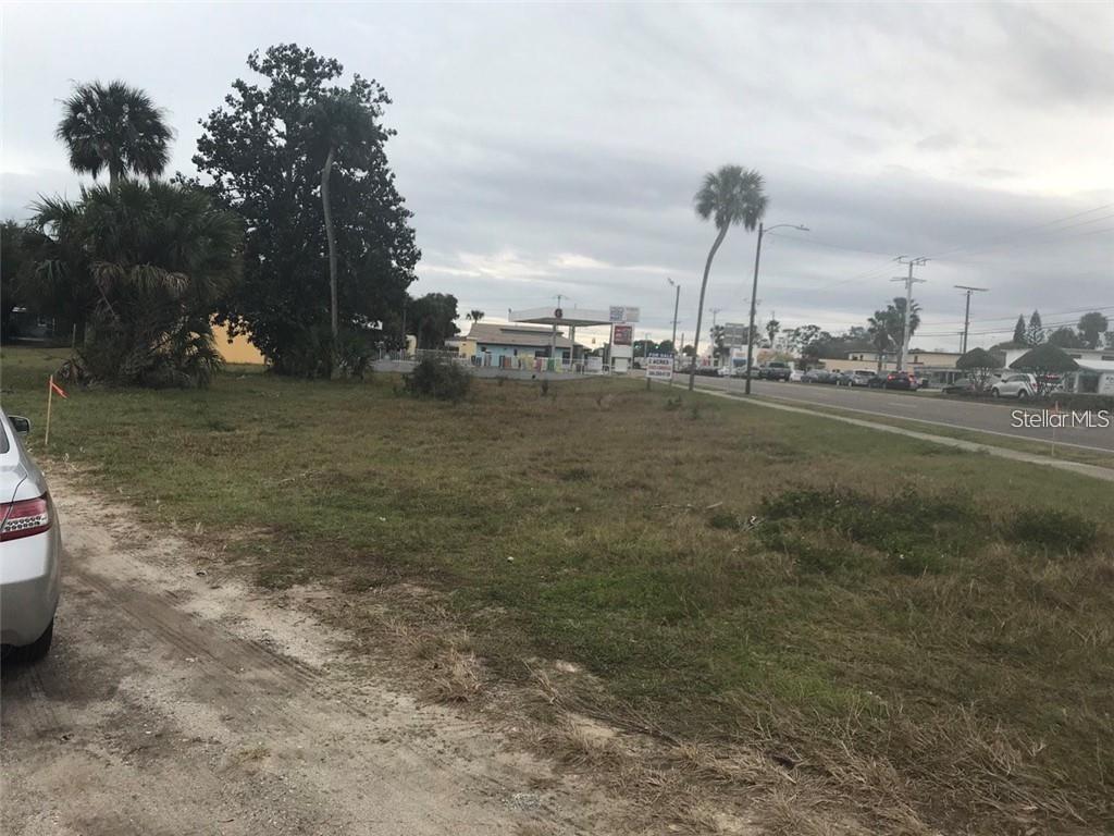 A vacant grassy lot sits next to a road with a gas station in the distance — 106 LAMONT STREET, EDGEWATER, FL