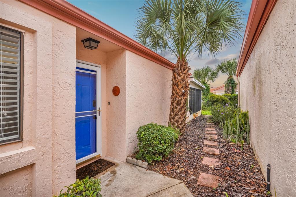 A pink stucco house exterior features a bright blue front door and a palm tree — 1704 SEA FAIR DRIVE, ST AUGUSTINE, FL