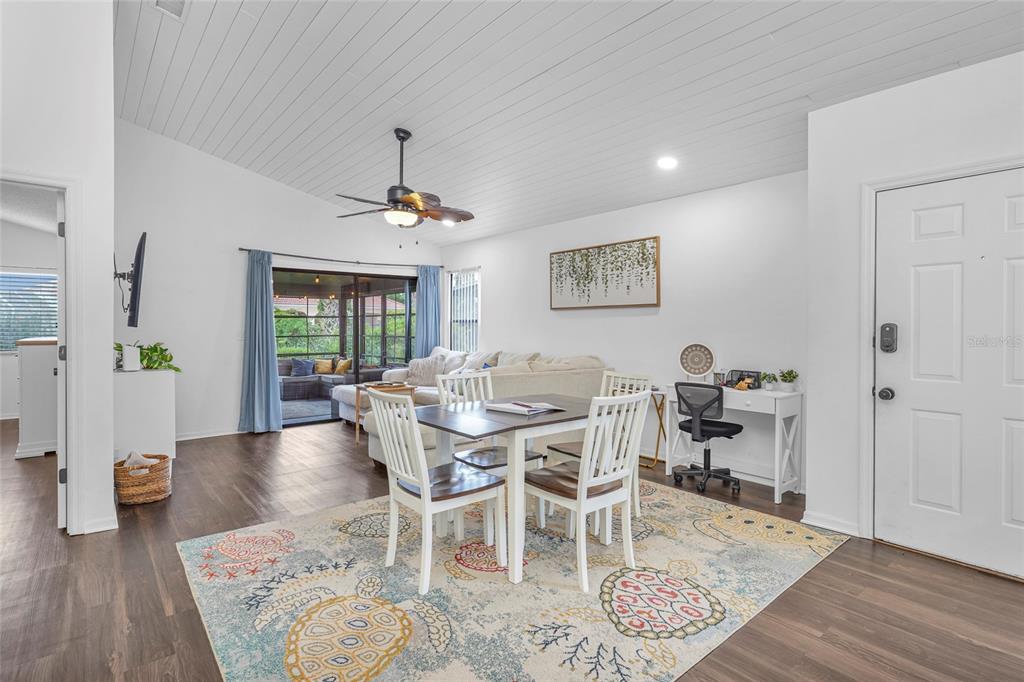 A dining area with a patterned rug sits in front of a living room and patio — 1704 SEA FAIR DRIVE, ST AUGUSTINE, FL