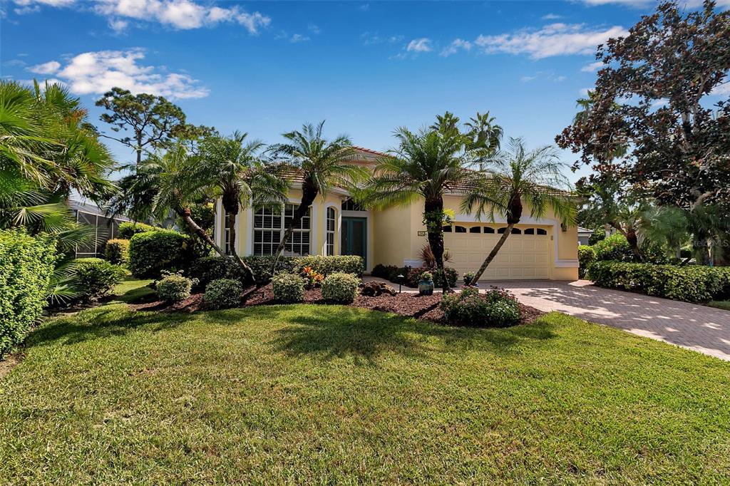 A single-story yellow house with a two-car garage and palm trees in the front yard — 21 BAYHEAD LANE, OSPREY, FL