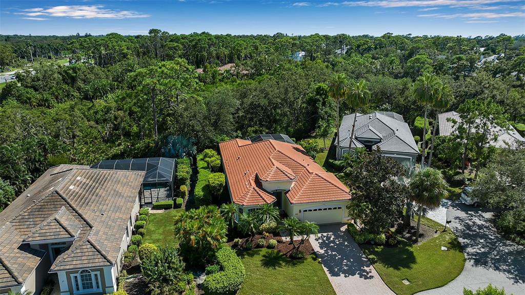 An aerial view shows three suburban homes surrounded by dense trees and lush landscaping — 21 BAYHEAD LANE, OSPREY, FL