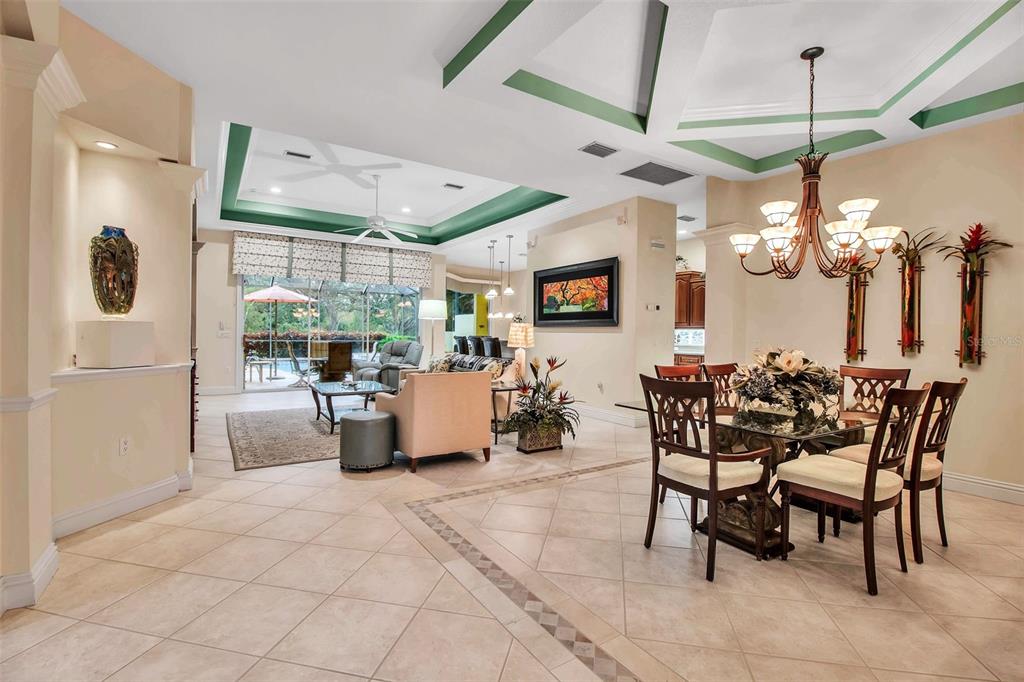 A spacious open-concept living and dining area features tile flooring, tray ceilings, and large windows — 21 BAYHEAD LANE, OSPREY, FL