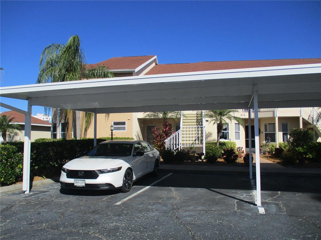 A white sedan is parked under a metal carport in front of a two-story apartment building — 1620 FAIRWAY TRACE UNIT A, PALMETTO, FL