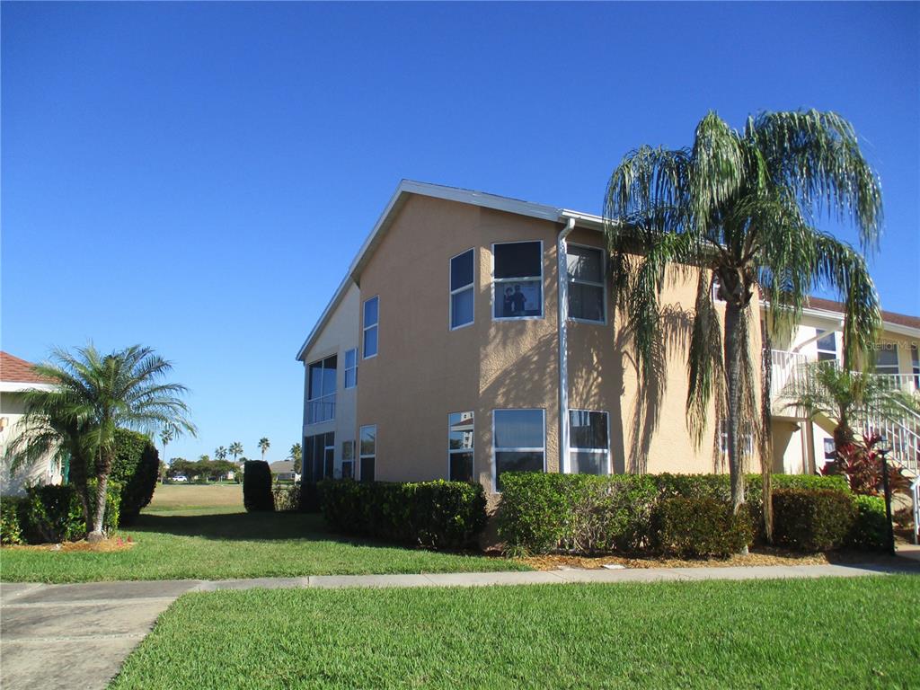 A two-story tan stucco residential building with a palm tree and landscaped hedges — 1620 FAIRWAY TRACE UNIT A, PALMETTO, FL